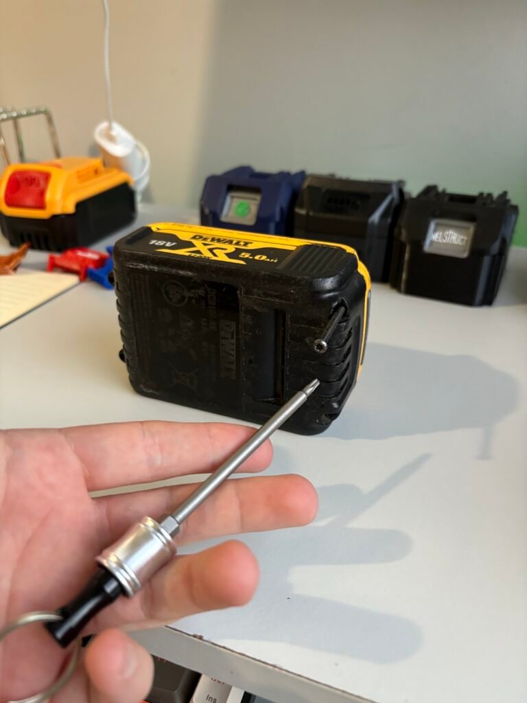 Using a T10 security Torx bit to undo the top cover screws during a cordless tool battery button replacement