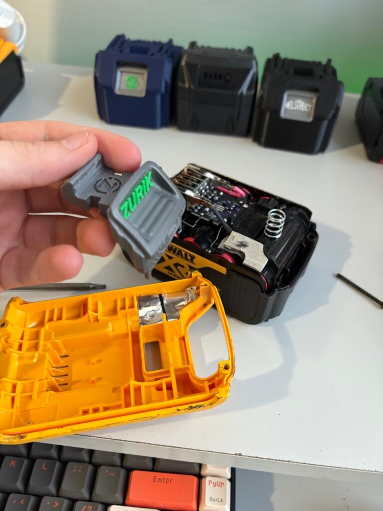 DeWalt 18V/20V XR battery top cover lifted off with the original battery release button visible before installing a custom replacement button